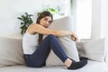 Young woman hugging pillow with depression and crying on sofa at home. Lonely millennial lady feeling stressed and hopeless, Royalty Free Stock Photo