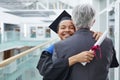 Young woman hugging professor at gradiation ceremony