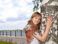 Young woman hugs birch in the summer