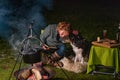 Young woman hugs her Australian Shepherd outside by a campfire. At dusk. Bread, cheese and wine on the table. Large Royalty Free Stock Photo