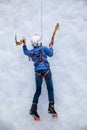 Young woman ice climber about to climb ice wall at ice climbing side-show attraction in Olympic Park in Sochi