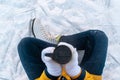 Young woman in ice skates sitting on the snow and holding mug with coffee. Close up of female hands. Royalty Free Stock Photo