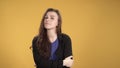 Young woman incredulously looking at the camera against yellow background