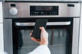 Young woman is indoors in smart house room controlling the oven Royalty Free Stock Photo