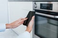 Young woman is indoors in smart house room controlling the oven Royalty Free Stock Photo