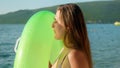 Young woman inflates her swim ring on a gorgeous sunset beach. Tourism, the joy of summertime, ocean escapes, and dreamy Royalty Free Stock Photo