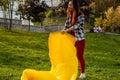 A Young woman Inflates A yellow Lamzac With Air. A woman Inflates An Air Sofa in park.