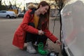 Young woman inflating car tire with air compressor on street Royalty Free Stock Photo