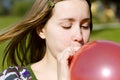 Young woman inflating red balloon