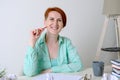 Young woman in informal clothes sits at a desk in front of a blank sheet of paper. Young woman writer at work