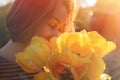 A young woman inhales the scent of spring flowers, yellow tulips. Concept of Allergy. Close up Royalty Free Stock Photo