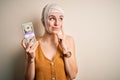 Young woman injured wearing bandage on head holding money from medical insurance payment serious face thinking about question, Royalty Free Stock Photo