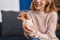 Young woman inserting coin on piggy bank at home Royalty Free Stock Photo