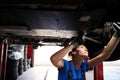 Young woman inspecting the underbody of a car Royalty Free Stock Photo