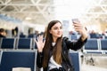 Young woman at international airport, making selfie with mobile phone and waiting for her flight. Female passenger at departure Royalty Free Stock Photo