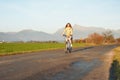 Young woman in jacket rides a bicycle over country road, afternoon sun shines at mount Krivan peak - Slovak symbol - background Royalty Free Stock Photo