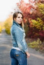 Young woman in jeans on the autumn road