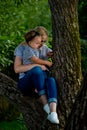 A young woman in jeans and a striped T-shirt and her little daughter are sitting on a tree Royalty Free Stock Photo