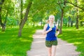 Young woman jogging in summer park and listening to music using smart phone Royalty Free Stock Photo