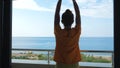 Young woman joins hands with palms together in namaste on the hotel balcony.