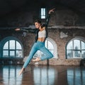 Young woman jumping in casual style - jeans and leather jacket doing ballet in old studio. Attractive ballerina Royalty Free Stock Photo