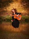 Young woman jumping with guitar Royalty Free Stock Photo