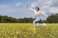 young woman jumping happy in a field of yellow flowers Royalty Free Stock Photo