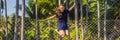 Young woman jumping on an outdoor trampoline, against the backdrop of palm trees BANNER, LONG FORMAT