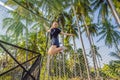 Young woman jumping on an outdoor trampoline, against the backdrop of palm trees