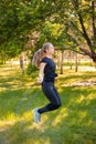 Young woman jumping rope on the lawn in a summer park. Jumping model. The concept of a healthy lifestyle and outdoor sports Royalty Free Stock Photo