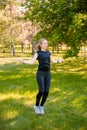 Young woman jumping rope on the lawn in a summer park. Jumping model. The concept of a healthy lifestyle and outdoor sports Royalty Free Stock Photo