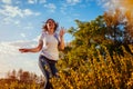 Young woman jumping, running and having fun in spring field at sunset. Happy and free girl relaxes and enjoys nature Royalty Free Stock Photo