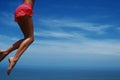 Young woman jumping on the tropical beach. Blue sky and slim legs