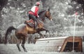 Young woman jumps a horse during practice on cross country eventing course, duotone art