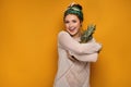 Young woman with a kerchief hugs a pineapple, yellow background