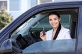 Young woman with key sitting in car. Buying new auto Royalty Free Stock Photo