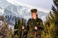 young woman in khaki uniform with walking sticks in mountains Royalty Free Stock Photo