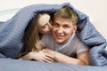 Young woman kisses his man husband in bed in the morning in the bedroom, young happy couple, family values