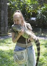 The young woman kisses an iguana, holds her on hands