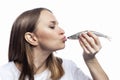 A young woman kisses a small raw fish. Health, vitamins and natural food. Close-up. Isolated on white background. Profile view