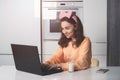 Young woman in a kitchen catching up and having fun while studying on a laptop computer. Distance Learning. Royalty Free Stock Photo