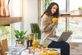 Young Woman in kitchen with laptop computer looking recipes, smiling. Food blogger concept