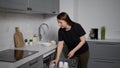 Young woman in the kitchen opens the dishwasher, loads and takes out dishes. Royalty Free Stock Photo