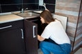 Young woman in kitchen during quarantine. Female person fixing pipe leaking under sink. Hold wrench in hand. Alone in Royalty Free Stock Photo