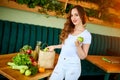 Young woman at kitchen taking out apple from grocery shopping paper bag with fruits and vegetables products Royalty Free Stock Photo