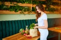 Young woman at kitchen taking out dill from grocery shopping paper bag with fruits and vegetables products Royalty Free Stock Photo