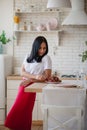 Young woman in kitchen taking strawberry from plate.