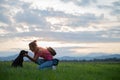 Young woman kneeling down to cuddle her cute black labrador puppy