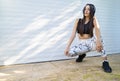 Young woman kneeling and posing with headphones next to white garage doors Royalty Free Stock Photo