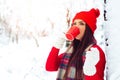 Young woman in a knitted shape is drinking tea in the forest during a snowfall. - Image